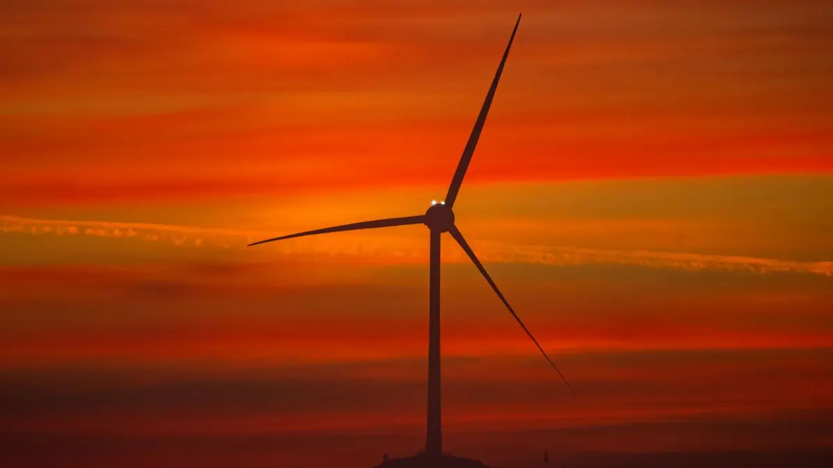 Sonnenaufgang hinter Windrad: ARCHIV - 13.09.2022, Bayern, München: Ein Windrad steht im Norden der bayerischen Landeshauptstadt kurz vor Sonnenaufgang am Horizont. (zu dpa: «Bayern fühlt sich bei Windrad-Vergabe vom Bund benachteiligt») Foto: Peter Kneffel/dpa +++ dpa-Bildfunk +++