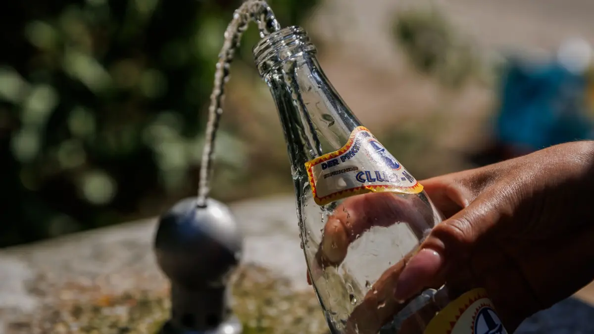 Hitze in Deutschland - Berlin: 26.06.2026, Berlin: Ein Fan des US-amerikanischen Musikers Bruno Mars fühlt auf dem Weg zum Konzert im Olympiastadion an einem Brunnen eine Wasserflasche auf. Derzeit rollt eine Hitzewelle über Brandenburg und Berlin. Foto: Carsten Koall/dpa +++ dpa-Bildfunk +++