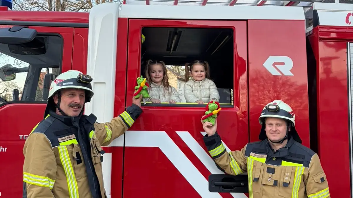 Michael Roth, rechts und sein Stellvertreter Reiner Kriehn bei der Übergabe des kleinen Feuerwehr-Grisu an die Kinder der Familie vom Kellerbrand.