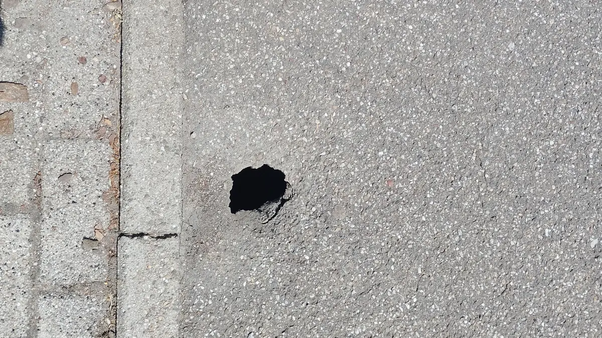 Im Gehweg in der Talstraße in Schömberg ist neben den Parkplätzen ein Loch im Asphalt.