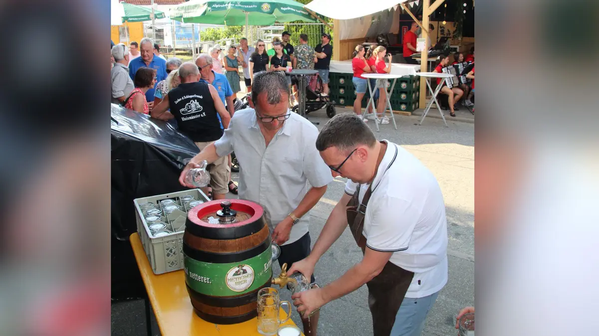Bürgermeister Peter Schumacher und Vereinsringsvorsitzender Stefan Schneider schenken gemeinsam das Bier vom Fassanstich aus.
