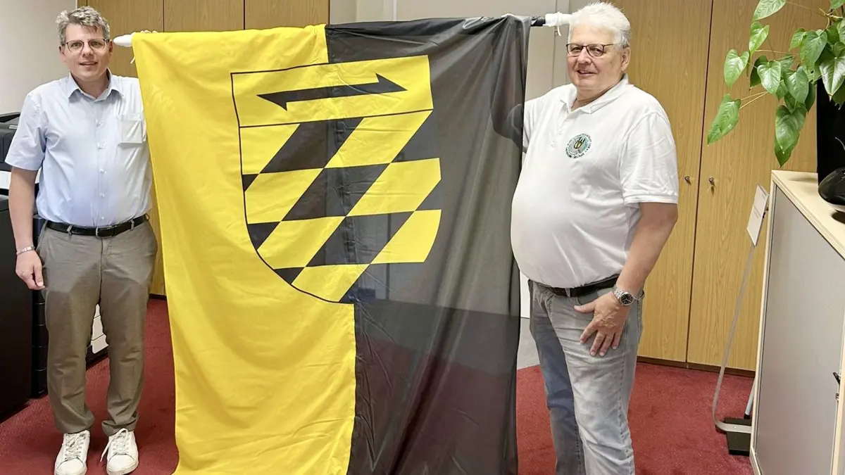 Bürgermeister Matthias Winter übergibt Vorstand Michael Märländer die neue Stadtfahne im Rathaus Oberndorf.