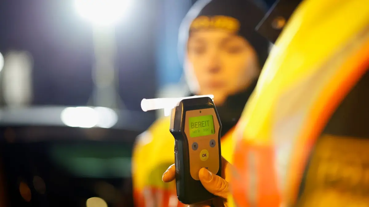 Polizei macht Alkoholtest: ARCHIV - 08.03.2024, Bayern, Aschaffenburg: Eine Polizistin misst den Atemalkoholgehalt eines Autofahrers mit einem Alkoholtester, um festzustellen, ob er möglicherweise unter Alkoholeinfluss steht. (zu dpa: «Schulbus-Fahrer mit 2,73 Promille gestoppt») Foto: Heiko Becker/dpa - ACHTUNG: Person(en) wurde(n) aus rechtlichen Gründen gepixelt +++ dpa-Bildfunk +++