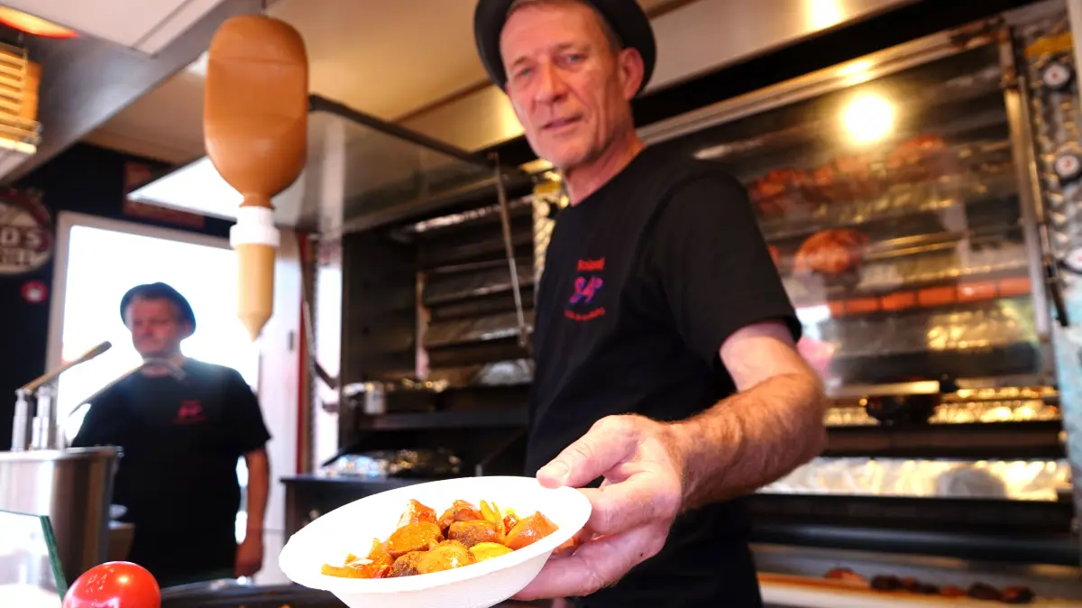 23.07.2020, Hamburg: Roland Schmidt, Inhaber von "84 Grad", hält in seinem Foodtruck eine Portion Currywurst mit Pommes in der Hand. Wegen der Corona-Krise warnen Gastronomen vor einer Pleitewelle in der Streetfoodszene. (Zu dpa: "Aufgeben oder weitermachen? Streetfood in Zeiten von Corona") Foto: Jonas Klüter/dpa +++ dpa-Bildfunk +++