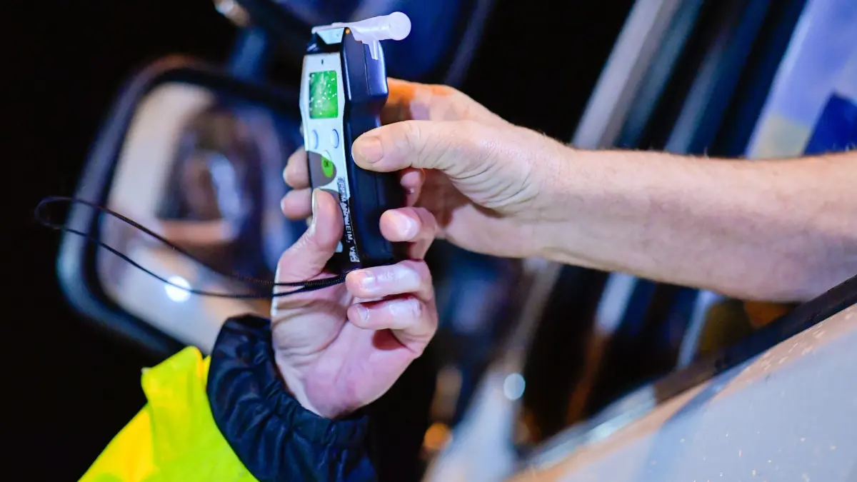 Alkoholkontrollen - Symbolbild: ARCHIV - 09.12.2018, Baden-Württemberg, Sinsheim: Ein Polizist reicht einem Lastwagenfahrer ein Alkoholmessgerät in die Fahrerkabine. (zu dpa: «Sturzbetrunkener Autofahrer setzt Wagen gegen Leitplanke») Foto: Uwe Anspach/dpa +++ dpa-Bildfunk +++