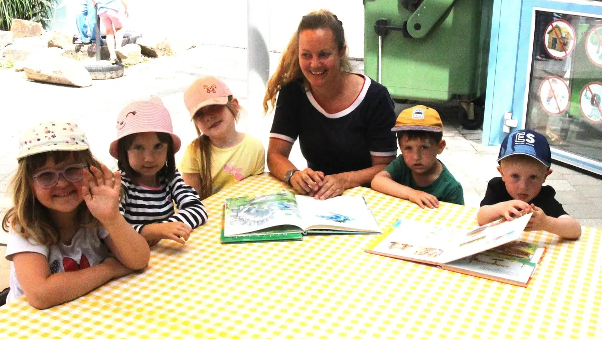 Die Kinder Hailey, Nika, Annabell, Erzieherin Carina Keller, Levin und Jaron beim Buch vorlesen im städtischen Kindergarten.