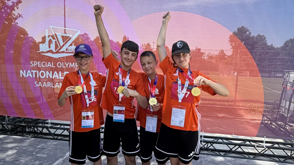 Die vier Schüler zeigen stolz ihre Goldmedaille aus dem 100-Meter-Lauf.
