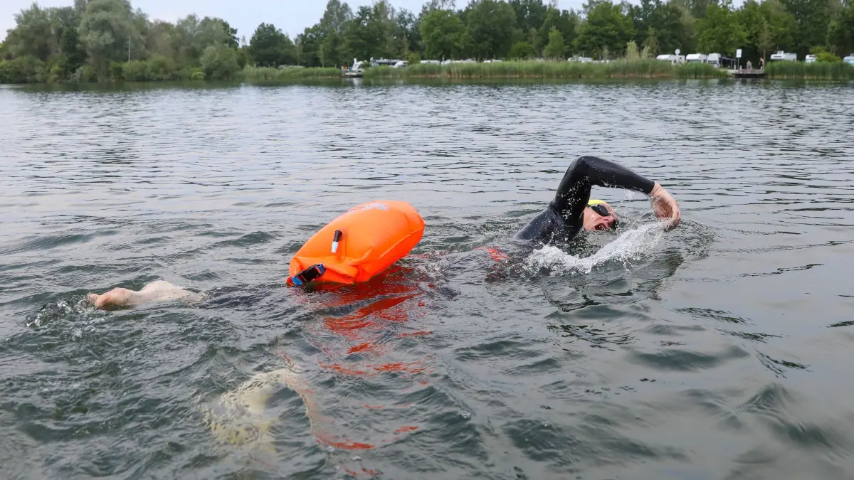 Ein Schwimmer mit einer Schwimmboje im See: ARCHIV - Praktisch, aber keine «Lebensversicherung»: An der Boje kann man sich bei Erschöpfung kurz festhalten – trotzdem bleiben Strömung und Schiffsverkehr gefährlich. (zu dpa: «Notfällen vorbeugen: Wie sinnvoll sind Schwimmbojen?») Foto: Thomas Warnack/dpa/dpa-tmn - Honorarfrei nur für Bezieher des dpa-Themendienstes +++ dpa-Themendienst +++