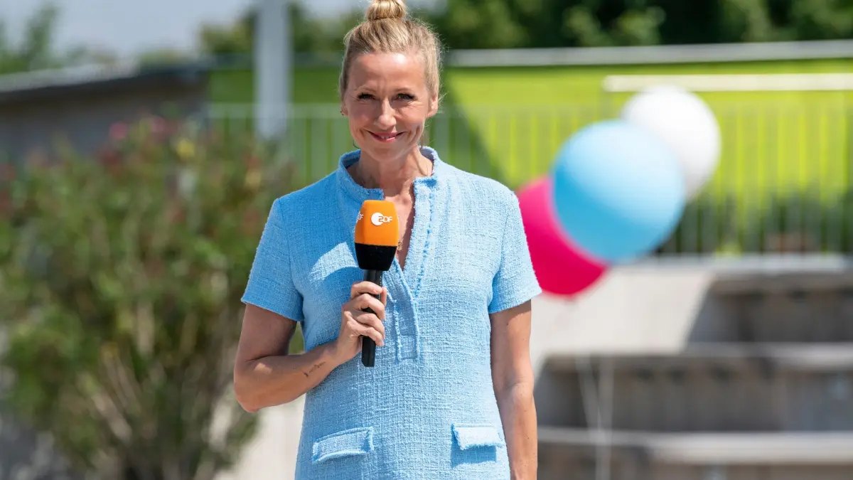 ZDF-Fernsehgarten: HANDOUT - 20.09.2023, Rheinland-Pfalz, Mainz: "ZDF-Fernsehgarten: Moderatorin Andrea Kiewel steht im "Fernsehgarten" und lächelt in die Kamera. Für ihr Gastspiel in Schwerin waren alle Tickets in Windeseile weg. (zu dpa: «Kiewel entschuldigt sich nach Äußerung im «Fernsehgarten»») Foto: Sascha Baumann/ZDF/dpa +++ dpa-Bildfunk +++