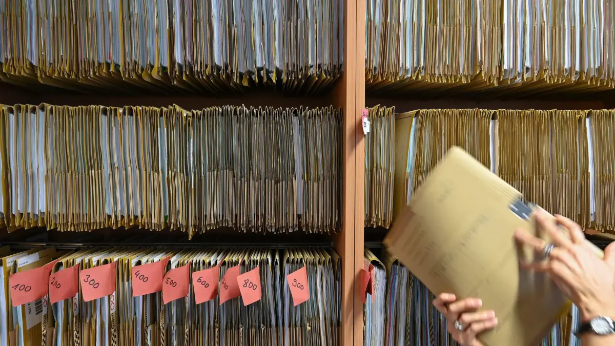 Bürokratie: ARCHIV - 27.07.2023, Hessen, Frankfurt/Main: Eine Mitarbeiterin einer Behörde greift an einem Regal nach einer Akte. (zu dpa: «Landesregierung zieht Zwischenbilanz zum Bürokratieabbau») Foto: Arne Dedert/dpa +++ dpa-Bildfunk +++