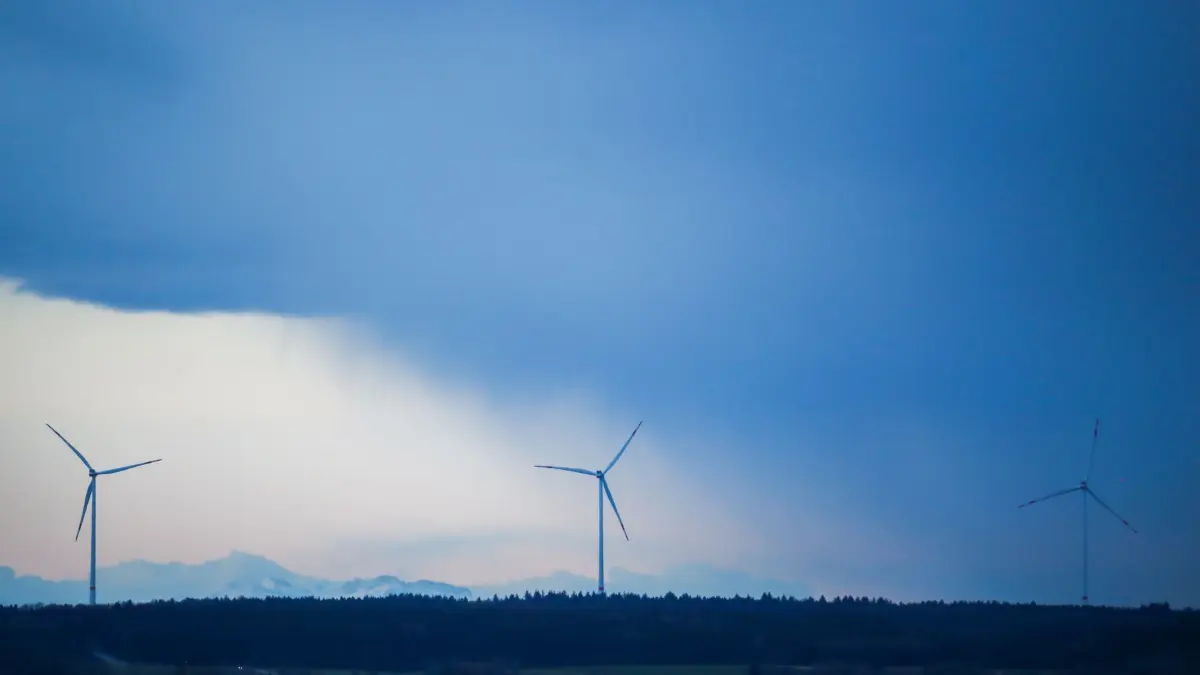 Windräder in Oberschwaben: ARCHIV - 10.03.2023, Baden-Württemberg, Seekirch: Hinter drei Windrädern ziehen Regenwolken auf. Durch die Föhnwetterlage sind die mehr als 100 Kilometer entfernten Alpen schemenhaft zu erkennen. (zu dpa: «Windkraftpionier Sowitec meldet Insolvenz an») Foto: Thomas Warnack/dpa +++ dpa-Bildfunk +++