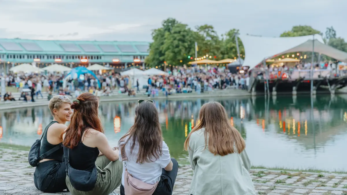 Vier Besucherinnen beobachten das Seefest 2025 vom Seeufer aus.