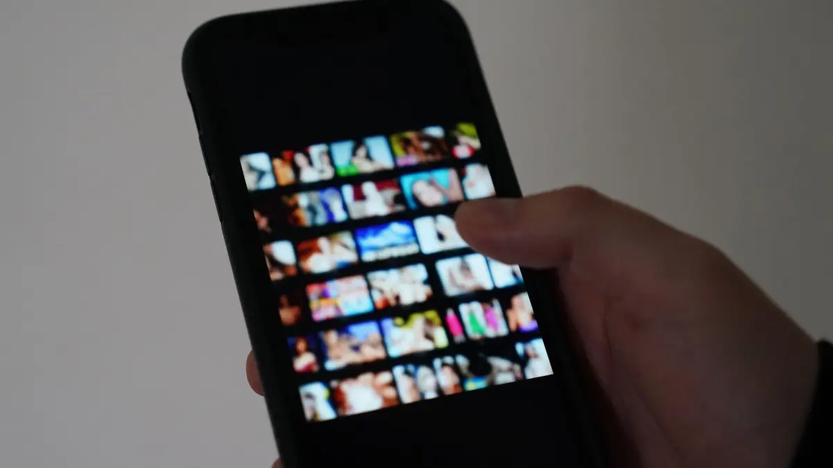Versuchte Erpressung mit Nacktbildern: ILLUSTRATION - 19.10.2023, Hamburg: Ein Mann schaut sich auf einem Smartphone eine Porno-Internetseite an (gestellte Szene). Es beginnt mit einem vermeintlichen Online-Flirt und endet mit Geldforderungen: Sextortion wird diese Form der Erpressung genannt. Es gibt Möglichkeiten, sich davor zu schützen. (zu dpa: «Erpressungsversuch mit Nacktbildern im Eichsfeld») Foto: Marcus Brandt/dpa +++ dpa-Bildfunk +++