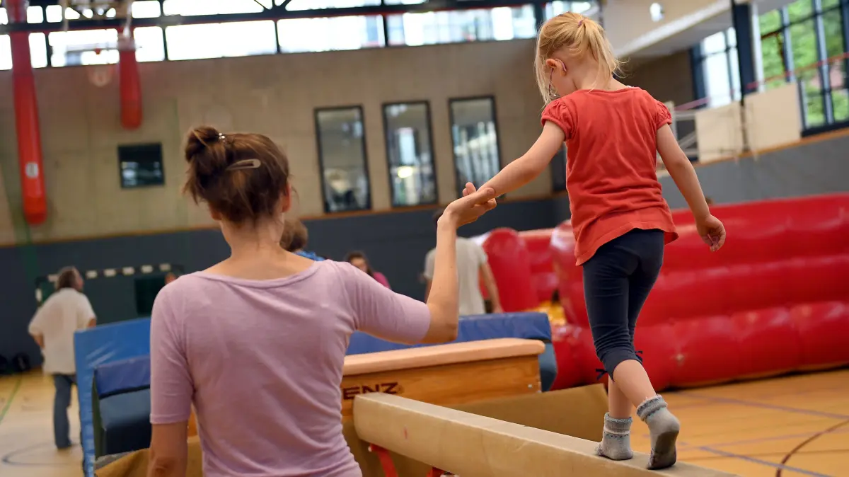 ARCHIV - 10.07.2017, Berlin: Eltern und Kinder turnen am 12.07.2017 beim Bambini-Sport des Sportvereins Pfeffersport e.V. (Eltern-Kind-Turnen) in einer Sporthalle in Berlin. (zu dpa: «Teilhabe-Zuschuss kommt bei Kindern im Saarland kaum an») Foto: Britta Pedersen/dpa-Zentralbild/dpa +++ dpa-Bildfunk +++