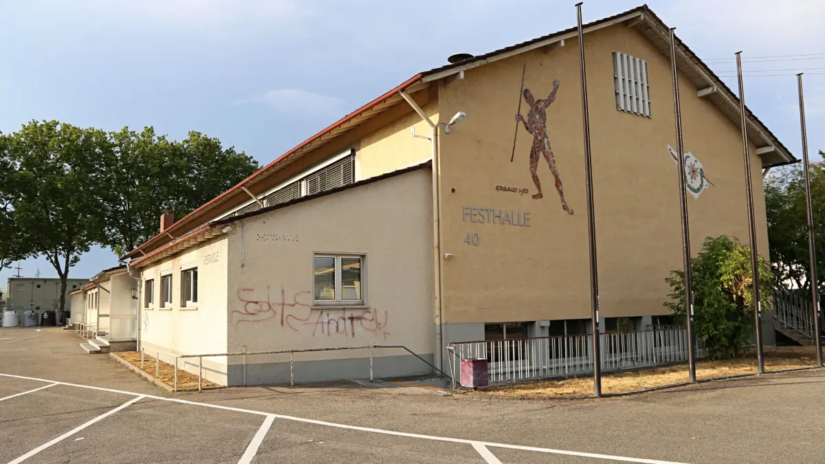 Die in die Jahre gekommene Festahalle in Haltingen, im Hintergrund stehen die Flüchtlingscontainer auf dem alten Sportplatz.