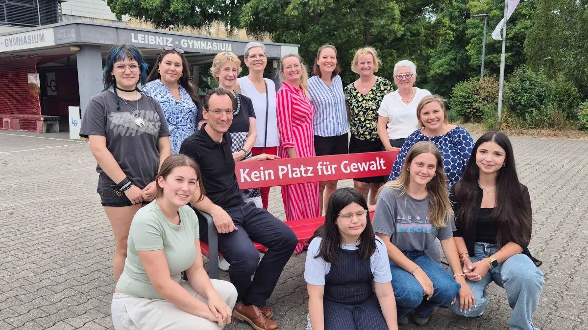 Emily Fuchs vom Vorstand des Vereins Frauen helfen Frauen + gegen Gewalt e. V. übergab gemeinsam mit Schulleitung Silke Pach, Seyma Kumtepe als Leitung der Courage AG und Schülerinnen des Leibniz-Gymnasiums die rote Bank, die künftig als sichtbares Zeichen gegen Gewalt auf dem Schulgelände steht.