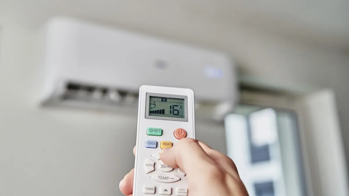 Ventilator und Fussbad statt Klimaanlage: Frau stellt mit einer Fernbedienung eine Klimaanlage ein (Foto vom 05.01.2022). Der Sommer in Deutschland geht weiter, viele Menschen wuenschen sich eine Klimaanlage. Experten schildern, warum ein einfacher Ventilator mehr Sinn macht und was Mietende zu beachten haben. (Siehe epd-Meldung vom 24.07.2026)