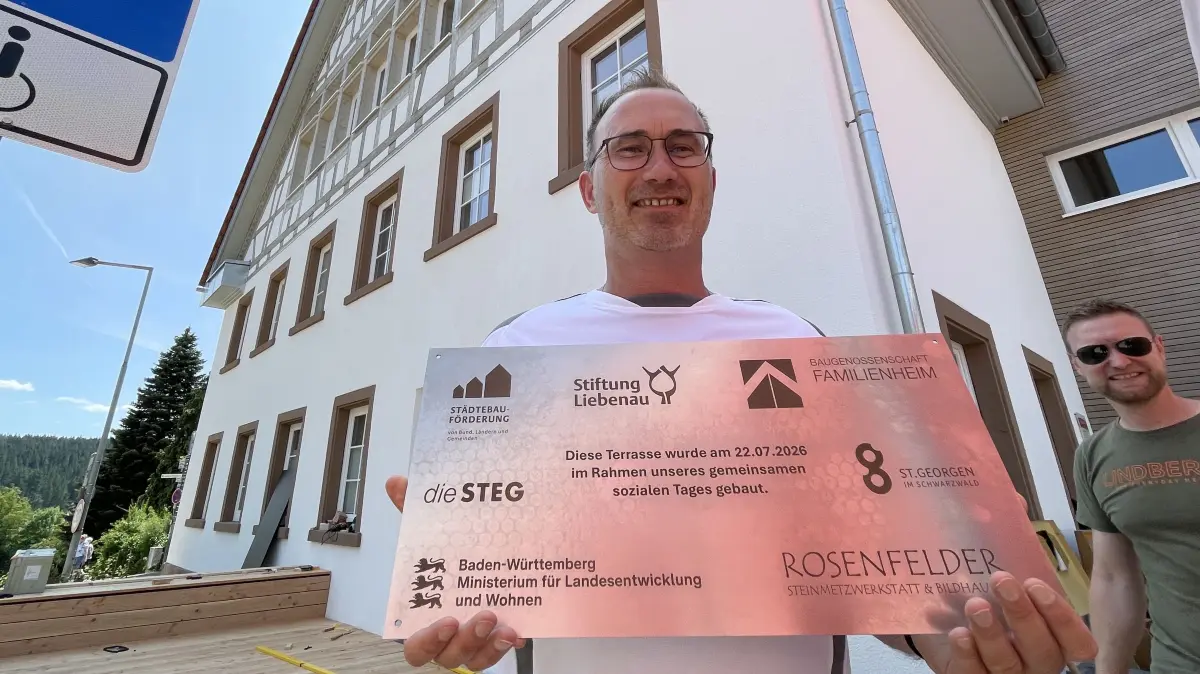 Mark Fischer von der Baugenossenschaft Familienheim präsentiert das Schild, das künftig an die Aktion erinnern soll.