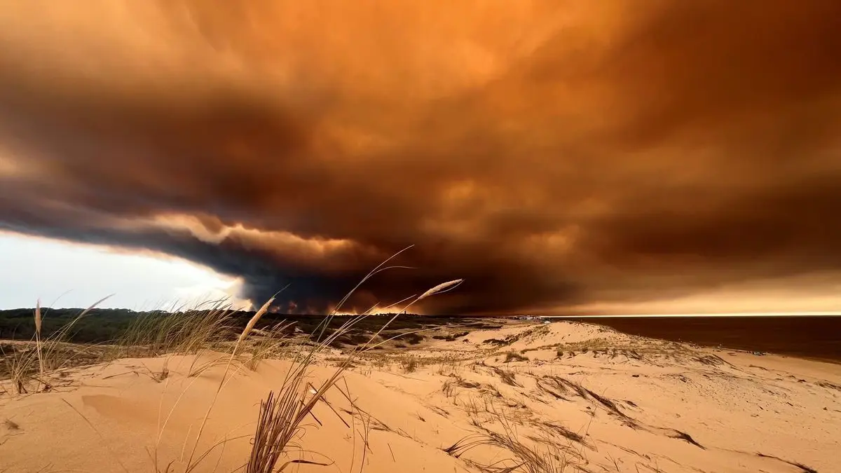 Rauchwolken von den Waldbränden südöstlich des Badeortes Lacanau-Ocean (hinten, r) verdunkeln den Himmel, während sie über die Dünen am Nordstrand hinwegziehen.