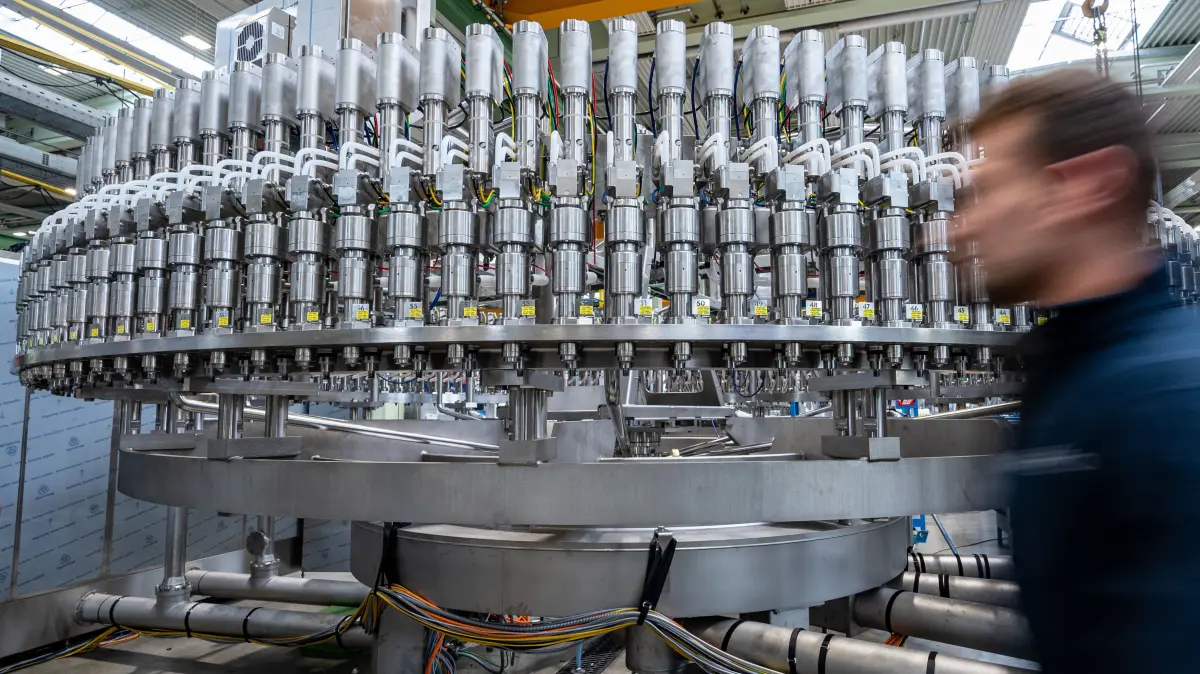 ARCHIV - 25.04.2022, Bayern, Neutraubling: Ein Mitarbeiter geht an einer Abfüllanlage in der Produktion eines Maschinenbauunternehmens vorbei. (zu dpa: «Rekordumsätze für bayerischen Maschinenbau») Foto: Armin Weigel/dpa +++ dpa-Bildfunk +++