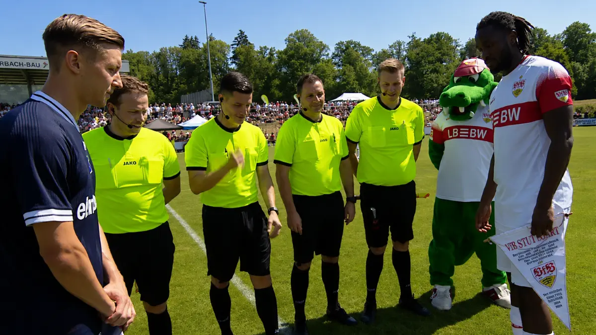 Wimpeltausch kurz vor dem Anpfiff (von links): Hollenbach-Kapitän Sebastian Schieck, Julius Wick, Lauritz Hafner, Sascha Wirth (vierter Offizieller von der Schiedsrichtergruppe Kocher/Jagst), Benjamin Haug, Maskottchen Fritzle und VfB-Kapitän Dan-Axel Zagadou