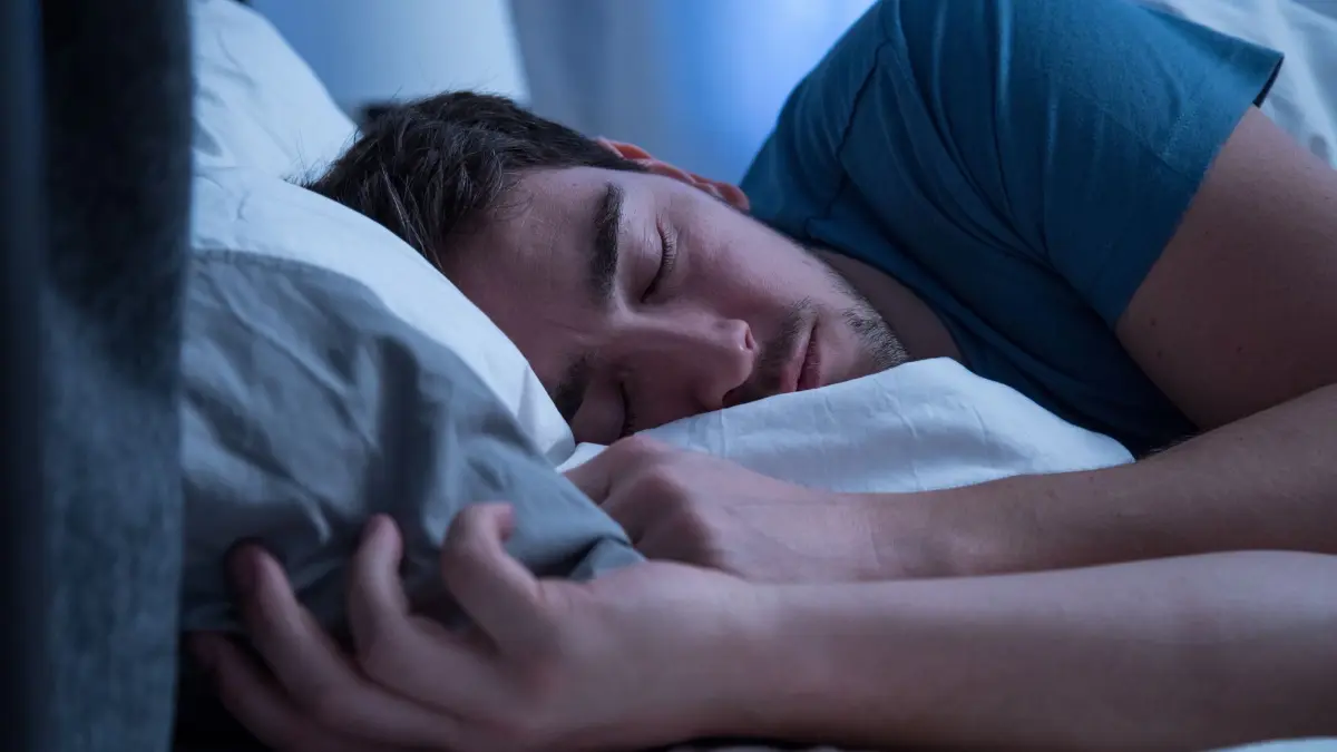 Mann schläft in einem Bett: ILLUSTRATION - Schichtarbeitende sollten ihren Schlaf ganz bewusst planen und für diese Zeit keine Termine machen. (zu dpa: «Schichtarbeit: Diese 8 Tipps helfen Körper und Psyche») Foto: Christin Klose/dpa-tmn - Honorarfrei nur für Bezieher des dpa-Themendienstes +++ dpa-Themendienst +++