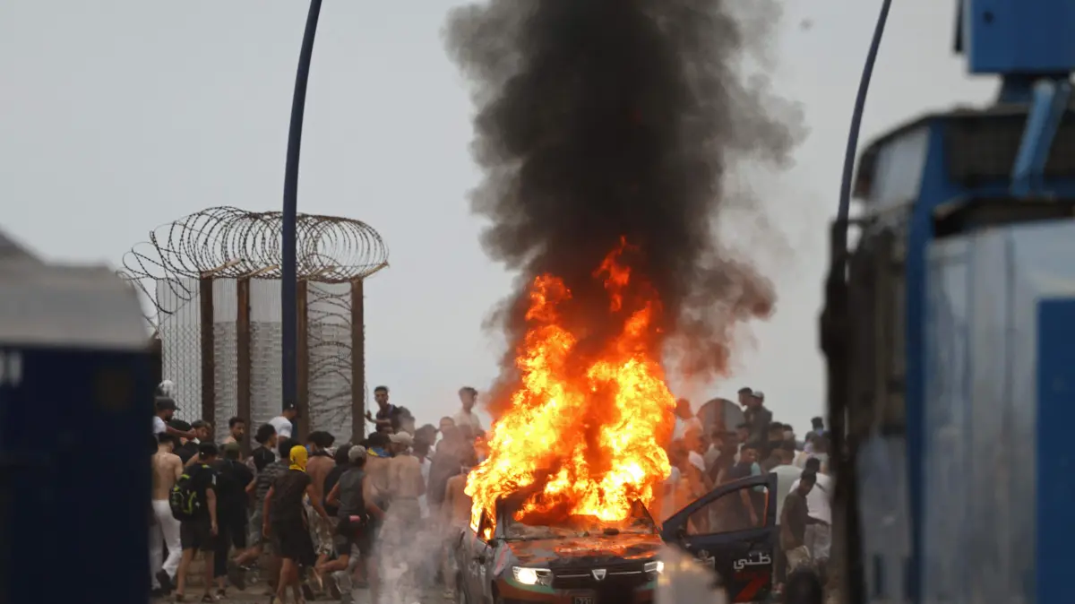 MOROCCO-SPAIN-MIGRATION: People gather at the site of clashes near Fnideq, on the Morocco-Spain border, on July 31, 2026. Thousands of migrants crossed overnight from Morocco into Spain's north Africa's Ceuta enclave, a police source said on July 31, adding that it was impossible to estimate how many people in total. A total of 18 people died while attempting to reach the Spanish enclave, the source said. (Photo by Abdel Majid BZIOUAT / AFP)