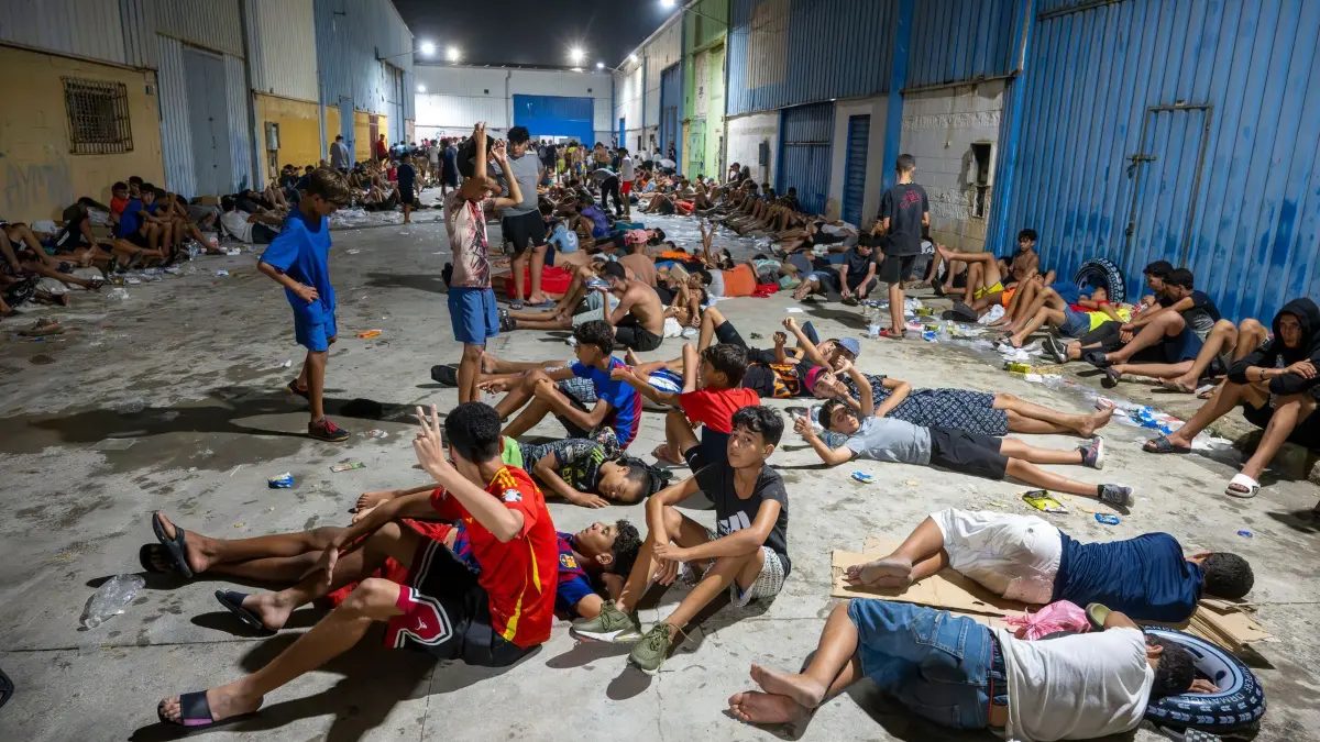 Migranten in Spanien - Exklave Ceuta: 31.07.2026, Spanien, Ceuta: Dutzende Migranten, die die Grenze zwischen Ceuta und Marokko überquert haben, verbringen die Nacht auf der Straße. Auch bei Einbruch der Dunkelheit am Donnerstag, dem 30. Juli, strömten weiterhin zahlreiche Menschen unkontrolliert aus Marokko nach Ceuta. Seit den frühen Morgenstunden hatten Tausende von Migranten die autonome Stadt erreicht, indem sie schwimmend oder zu Fuß die Mole umgingen, die die autonome Stadt von Marokko trennt. Foto: Marcos Moreno/EUROPA PRESS/dpa +++ dpa-Bildfunk +++