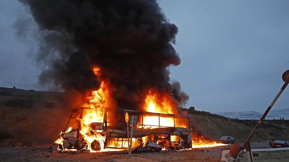 MOROCCO-SPAIN-MIGRATION: A vehicle burns at the site of clashes near Fnideq, on the Morocco-Spain border, on July 31, 2026. Thousands of migrants crossed overnight from Morocco into Spain's north Africa's Ceuta enclave, a police source said on July 31, adding that it was impossible to estimate how many people in total. A total of 18 people died while attempting to reach the Spanish enclave, the source said. (Photo by Abdel Majid BZIOUAT / AFP)