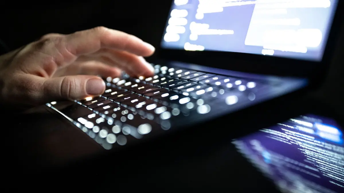 Cyberangriff: ILLUSTRATION - 14.12.2025, NA, Berlin: Eine Person tippt mit den Fingern auf einer beleuchteten Laptop-Tastatur. (gestellte Szene) (zu dpa: «Medien: Iran könnte hinter Cyberangriff auf US-Infrastruktur stecken») Foto: Philip Dulian/dpa +++ dpa-Bildfunk +++