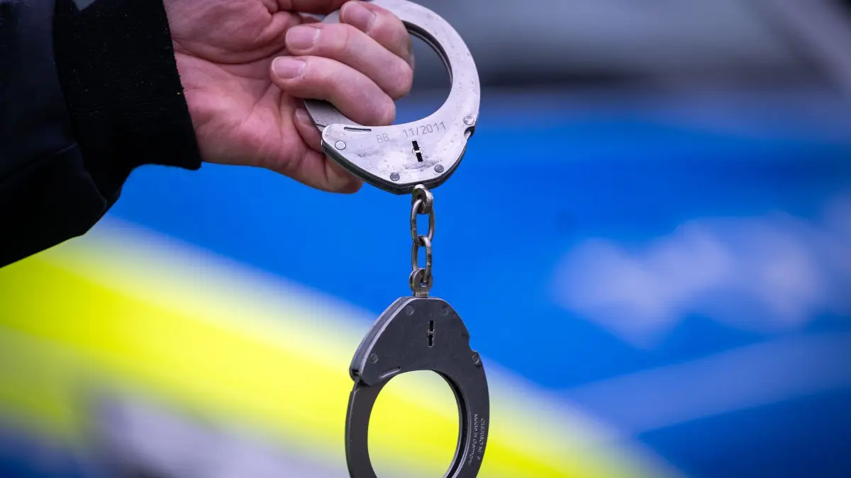 Festnahme (Symbolbild): ARCHIV - 22.03.2024, Brandenburg, Trebbin: Ein Polizist hält ein Paar Handschellen. (zu dpa: «Mann schlägt Polizisten ins Gesicht – zwei Beamte verletzt») Foto: Soeren Stache/dpa +++ dpa-Bildfunk +++