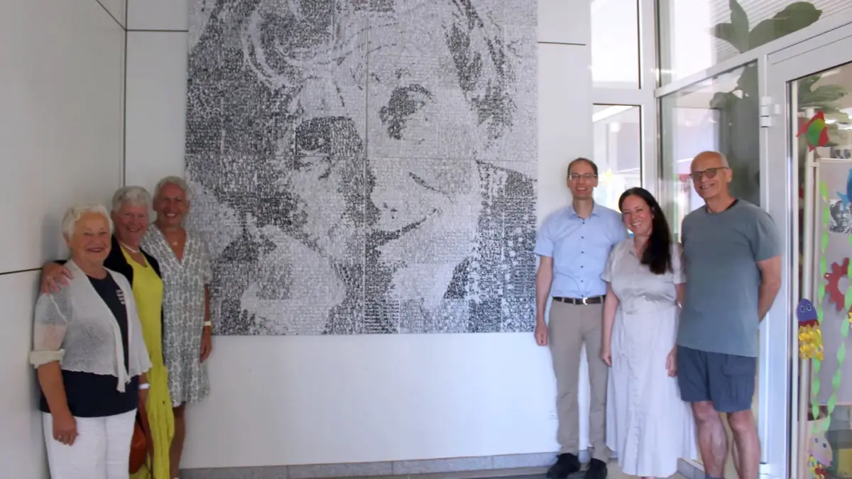 Eli Vogelsang, Sigrid Steiner, Ulla Böhm, Bürgermeister Torben Dorn, Rektorin Kathrin Michl und Hermann Schmutte (von links) stehen vor dem Kunstwerk in der Astrid-Lindgren-Schule. Das Bild besteht aus vielen kleinen Patches, die die Schüler beschriftet haben.