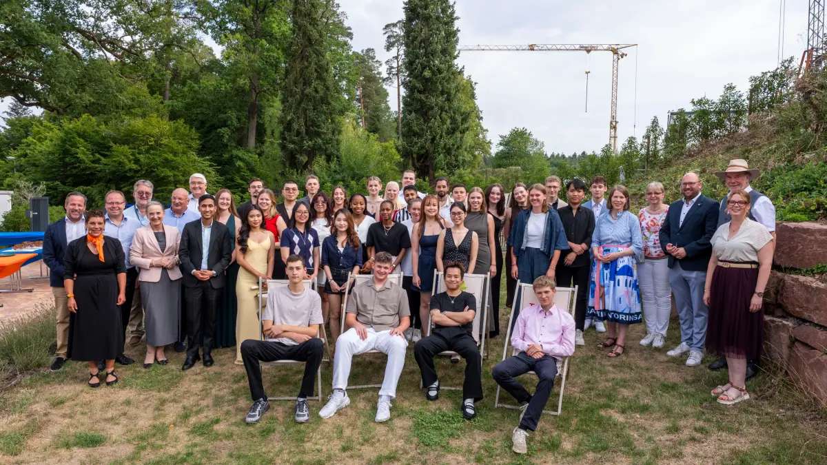 Die Absolventinnen und Absolventen in mehreren Berufsfeldern der Hotellerie und Gastronomie feiern auf dem Freigelände des Dehoga-Campus in Calw-Wimberg ihren erfolgreichen Abschluss. Eingerahmt werden sie von einigen Ehrengästen.