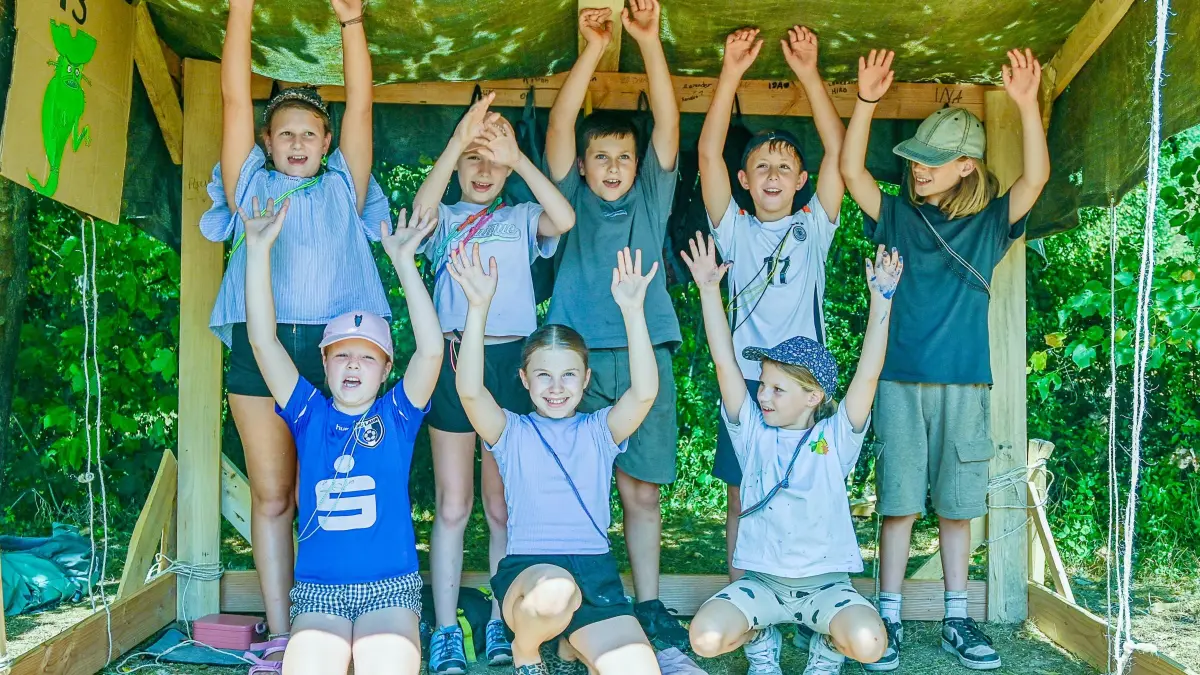 Die Kinder freuen sich nach bestandener Prüfung über ihre stabile Hütte.