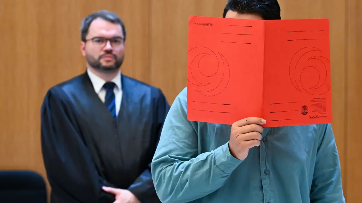 Prozess wegen Auto-Anschlag auf eine Demonstration: 06.08.2026, Bayern, München: Der Angeklagte Farhad N. (r) steht zu Prozessbeginn mit seinem Anwalt Johann Bund im Prozesssaal. Foto: Sven Hoppe/dpa +++ dpa-Bildfunk +++