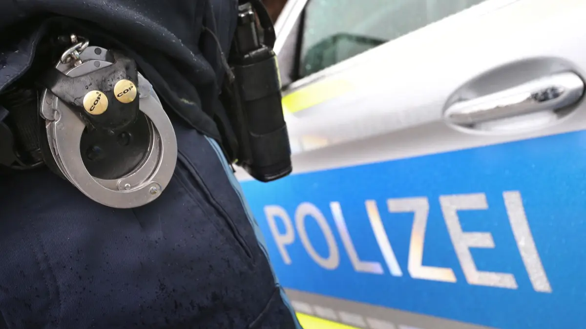 Polizei Symbolbild: ARCHIV - 15.03.2019, Bayern, Kempten: Ein Polizist mit Handschellen und einer Pistole am Gürtel steht vor einem Streifenwagen. (zu dpa: «Nach Messerangriff stellt sich Tatverdächtiger der Polizei») Foto: Karl-Josef Hildenbrand/dpa +++ dpa-Bildfunk +++