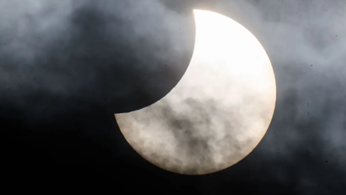 Partielle Sonnenfinsternis: ARCHIV - 25.10.2022, Niedersachsen, Laatzen: Eine partielle Sonnenfinsternis ist zwischen Wolken am Himmel zu sehen. (zu dpa: «Sonnenfinsternis: Fünf Tipps, um nicht im Dunkeln zu tappen») Foto: Julian Stratenschulte/dpa +++ dpa-Bildfunk +++