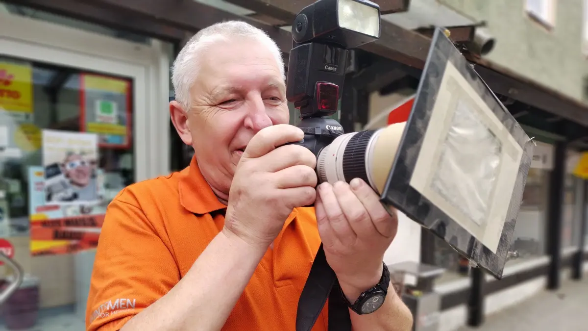 Fotograf Folke Weber mit seiner Kamera, auf die er einen Selbst gebastelteten Filter aufsetzt, den er schon 1999 benutzt hat.