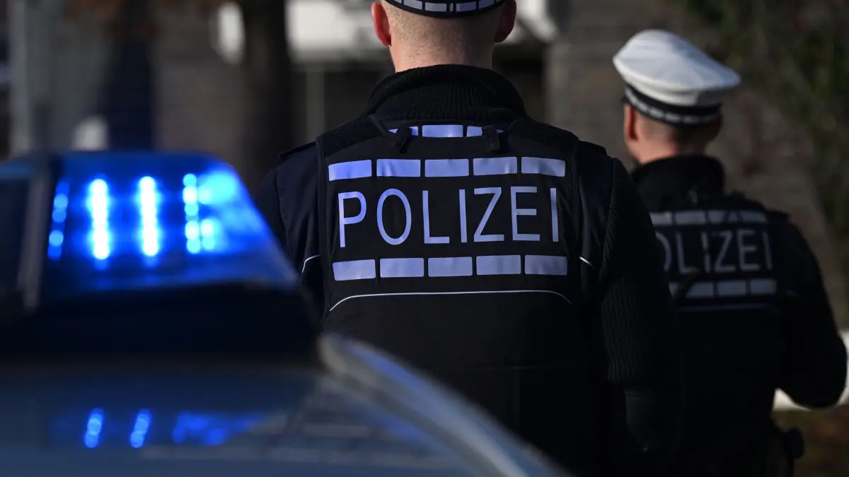 Polizei: ARCHIV - 03.12.2024, Baden-Württemberg, Stuttgart: Das Logo der Polizei ist auf der Dienstkleidung von Polizisten zu sehen, die vor einem Blaulicht stehen (gestellte Szene). (zu dpa: «Auf 33-Jährigen geschossen: Verdächtiger in U-Haft») Foto: Bernd Weißbrod/dpa +++ dpa-Bildfunk +++