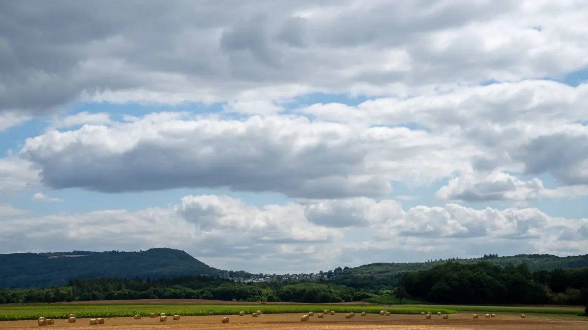 Wetter in Rheinland-Pfalz: ARCHIV - 19.07.2026, Rheinland-Pfalz, Wittlich: Dichte Wolken ziehen über ein abgeerntetes Getreidefeld, auf dem gepresste Strohballen liegen. Die Temperaturen sind in Rheinland-Pfalz deutlich gesunken, das Wetter wechselhaft. (zu dpa: «Gewitter sorgen für Abkühlung nach der Hitze») Foto: Harald Tittel/dpa +++ dpa-Bildfunk +++