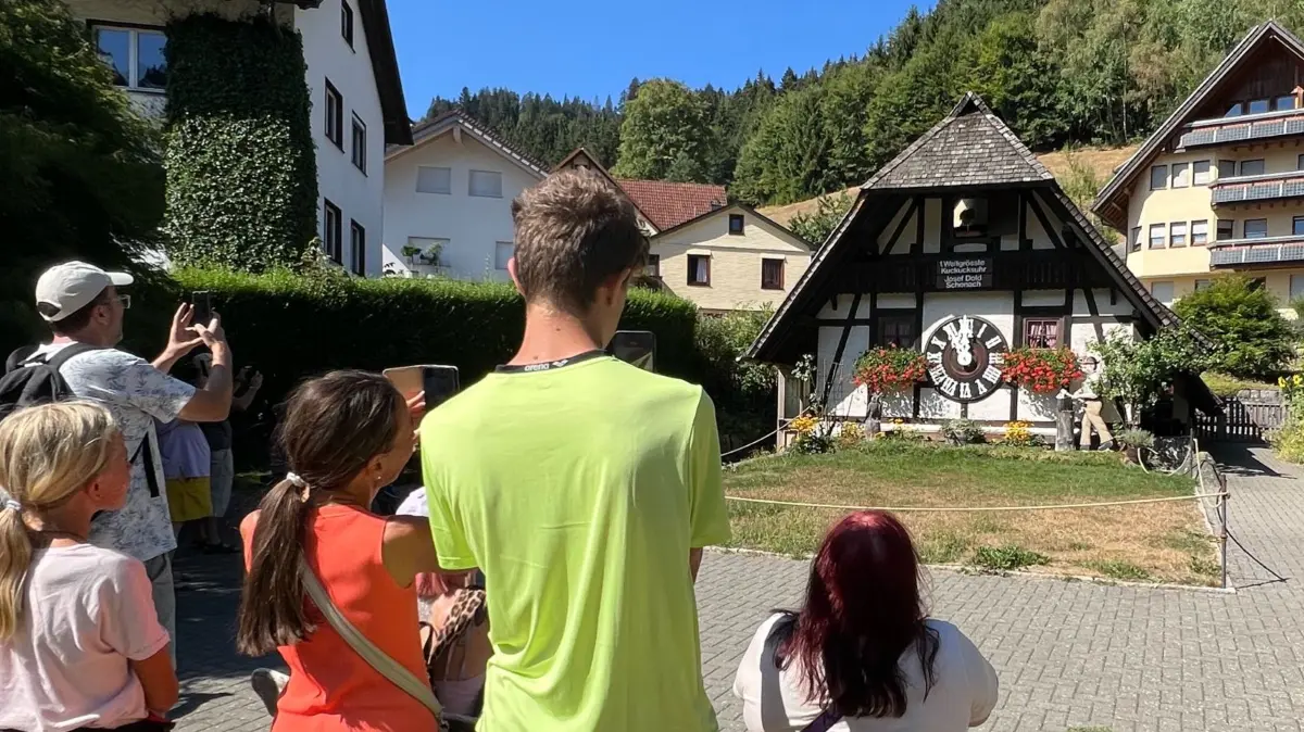 Touristen in Schonach fotografieren zur vollen Stunde die "1. weltgrößte Kuckucksuhr".