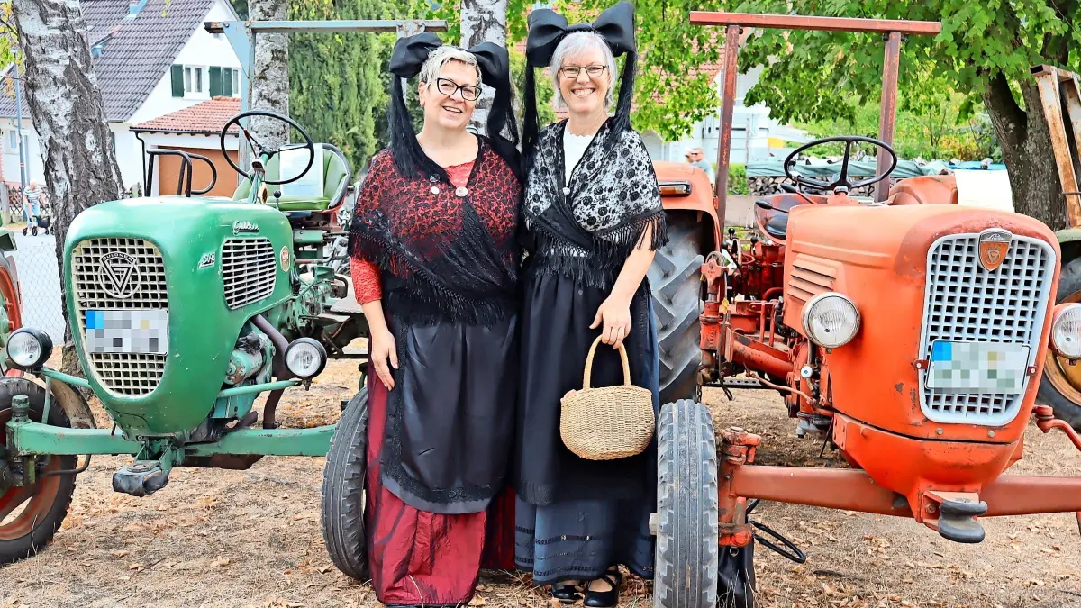 Zwei Trachtenträgerinnen inmitten historischer Fahrzeuge beim Oldtimertreffen beim Strübli-Fest in Wollbach