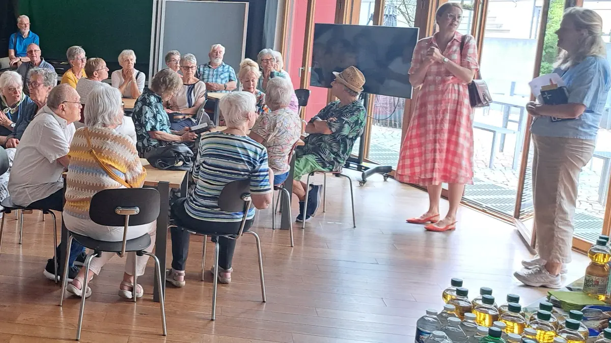 Infos und Gugelhupf gab’s bei einer Pause im Werkraum Schöpflin: Werkraum-Leiterin Esther Mikuszies (r.) erläuterte unter anderem den Stand der Dinge auf dem Fabric-Areal, Monika Neuhöfer-Avdic (2.v.r.) moderierte die Fahrt und informierte die Senioren über medizinische Versorgung und aktuelle Projekte der Stadtentwicklung.