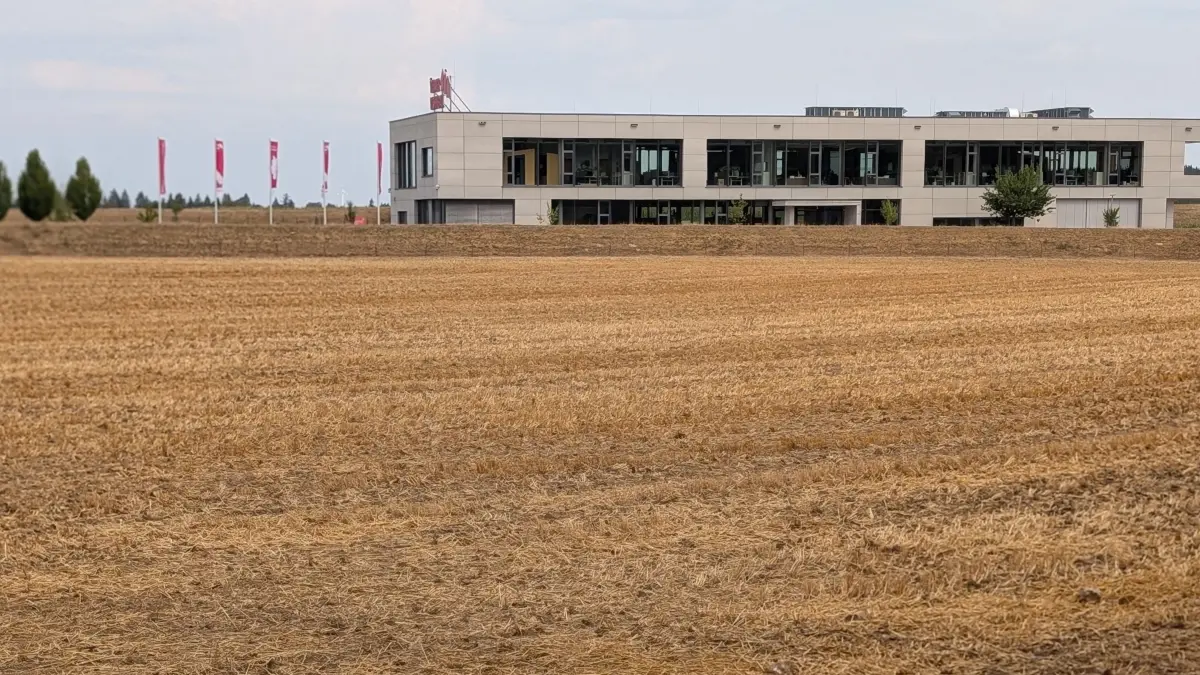Auf diesem Areal (Stoppelfeld) plant die Firma Werner Wohnbau, deren Stammsitz im Hintergrund zu sehen ist, eine Großinvestition in Form einer Produktionshalle.