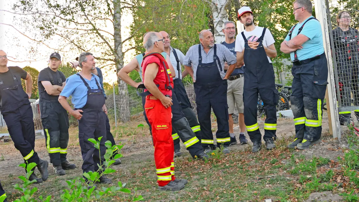 DLRG-Bezirkseinsatzleiter Norbert Dietrich (rotes Shirt) erläutert den Einsatzkräften der Feuerwehr das Vorgehen bei einer Wasserrettung.