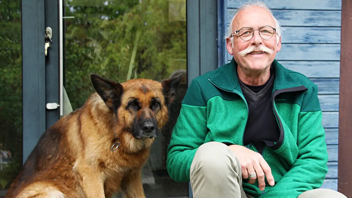 Bernd Brohammer mit seinem Hund auf der Treppe vor seinem Haus