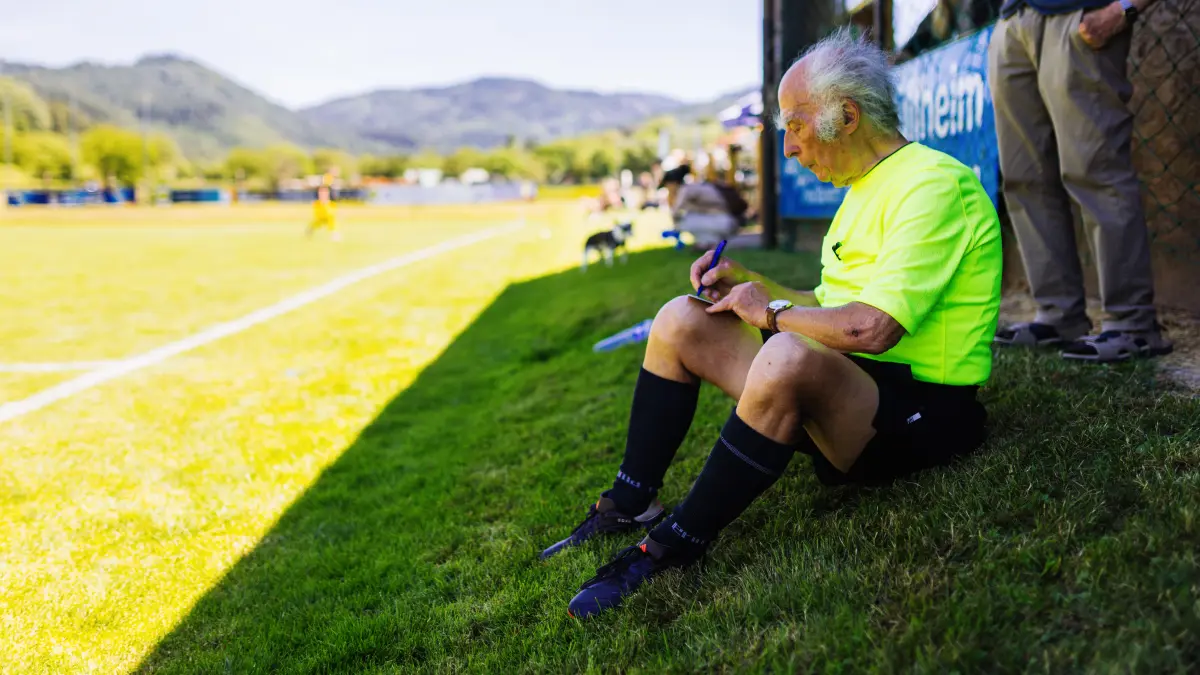 PRODUKTION - 14.06.2026, Baden-Württemberg, Müllheim: Werner Ziebold sitzt in einer Pause neben dem Spielfeld und notiert sich etwas. Jahrelang pfiff Ziebold vom SV Weilertal in der Kreisliga. Jetzt geht er im Alter von 90 Jahren in Rente. (zu dpa: «Letzter Pfiff mit 90 Jahren - Schiedsrichter geht in Rente») Foto: Philipp von Ditfurth/dpa +++ dpa-Bildfunk +++