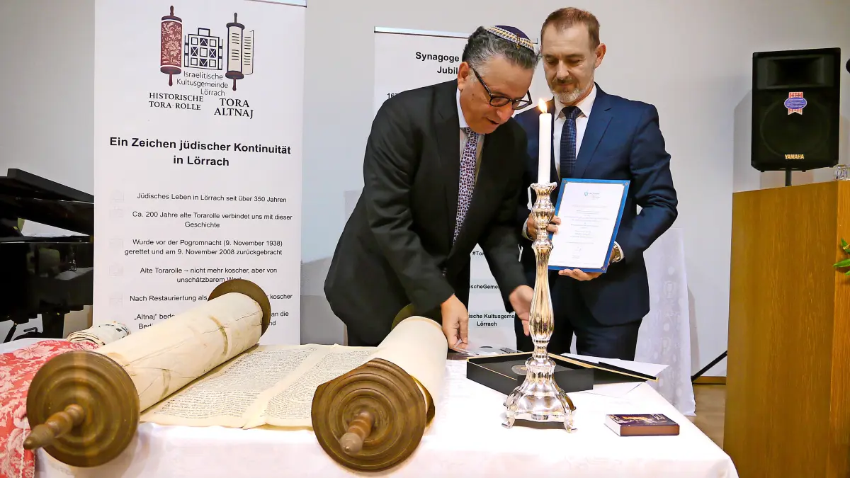 Das Foto zeigt Oberbürgermeister Jörg Lutz (r.) und Rami Suliman, den Vorsitzenden der Israelitischen Religionsgemeinschaft in Baden. Anlass war der 30. Jahrestag der Wiedergründung der Israelitischen Gemeinde im Herbst 2025. Dabei wurde die alte Rolle auf dem Podium präsentiert.