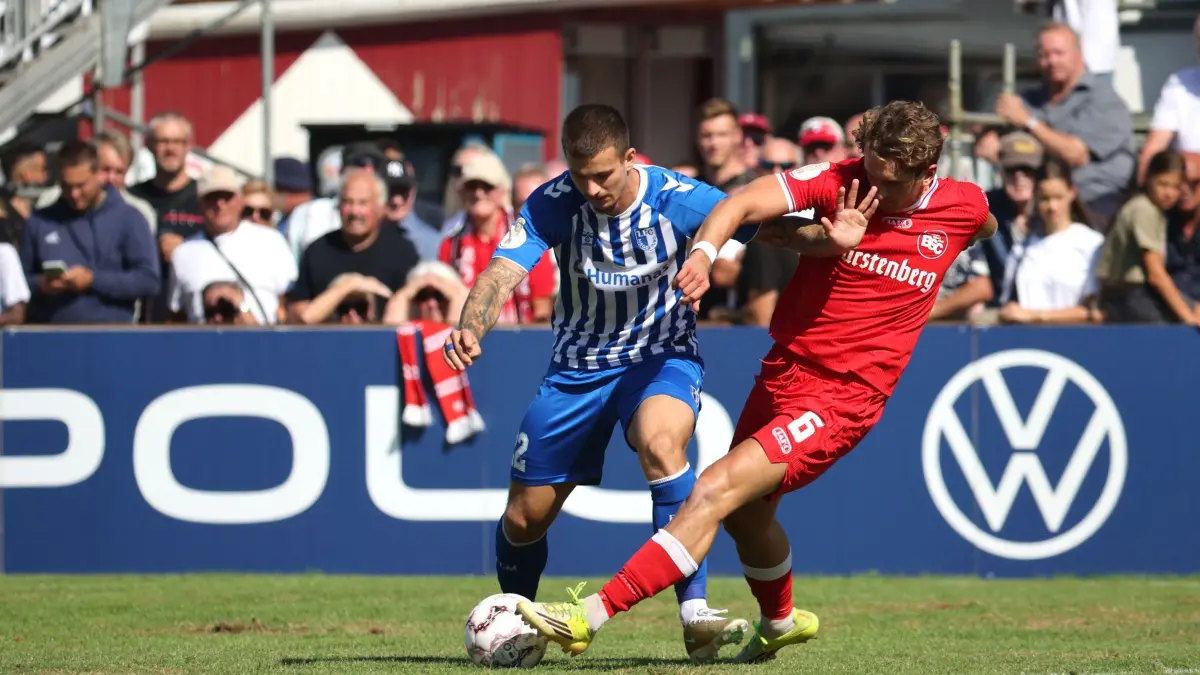 Bahlinger SC - 1. FC Magdeburg: 23.08.2026, Baden-Württemberg, Bahlingen am Kaiserstuhl: Fußball, Männer: DFB-Pokal, Bahlinger SC - 1. FC Magdeburg, 1. Runde, im Kaiserstuhlstadion, Mateusz Żukowski (1. FC Magdeburg) und Holger Bux (Bahlinger SC) kämpfen um den Ball. Foto: Philipp von Ditfurth/dpa - WICHTIGER HINWEIS: Gemäß den Vorgaben der Bundesliga bzw. des DFB Deutscher Fußball-Bund ist es untersagt, in dem Stadion und/oder vom Spiel angefertigte Fotoaufnahmen in Form von Sequenzbildern und/oder videoähnlichen Fotostrecken zu verwerten bzw. verwerten zu lassen. +++ dpa-Bildfunk +++