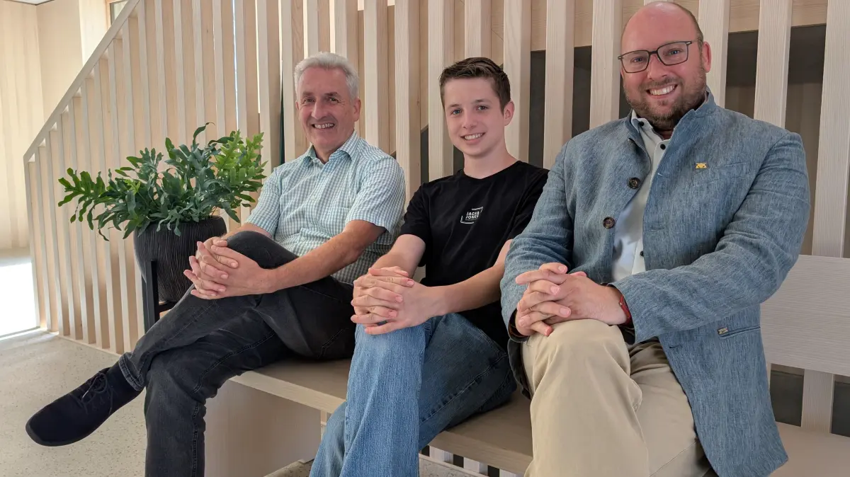 Simmersfelds Bürgermeister Jochen Stoll und Landtagsabgeordneter Carl Christian Hirsch auf der Bank aus heimischer Weißtanne im neuen Bürgerzentrum nach dem intensiven Austausch, begleitet von Praktikant Maximilian Smykalla (Bildmitte).